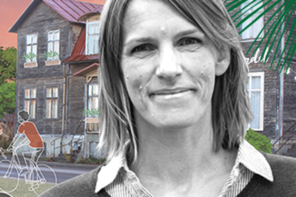 Porträttbild på Maria som ler med ett ödehus som har fått nytt liv som bakgrund.