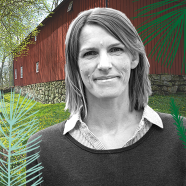 Porträttbild på Maria som ler med en lada i ett grönskande landskap som bakgrund.
